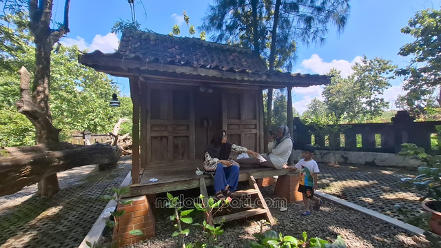 Wahyoeningsih menikmati rumah kayu jati kuno di taman Kayangan Api, Desa Sendahrjo, Ngasem. foto : Rinna H.